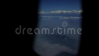在雪山和云层上形成一个飞机窗口的视图。